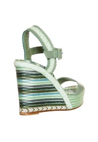 Sandalia cuña de cuero verde con un diseño de tiras, que presenta una plataforma de rayas multicolores y detalles trenzados en el borde.