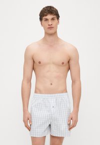 Modro-beli karo boksarji z elastiko v pasu in z enim gumbom za zapiranje, izdelani iz lahkega bombažnega blaga.