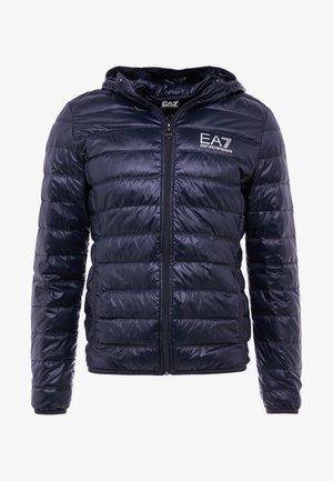 Giacca a vento blu navy con cappuccio, design trapuntato, chiusura con zip e logo EA7 sul petto. Il materiale sembra lucido e liscio.