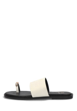 Sandalia plana negra con una ancha tira blanca sobre el pie y una delgada correa para el dedo del pie con una pequeña hebilla dorada.