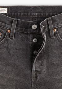 Zwarte denim jeans met een hoge taille, voorzien van koperen en zilveren hardware, een sluiting met vijf knopen en een vervaagde textuur.