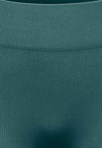 Κοντινή λήψη υφάσματος ριπ σε τιρκουάζ χρώμα που δείχνει πυκνή πλέξη και λεπτομέρεια ραφής σε στρογγυλεμένη λαιμόκοψη ή άκρη μέσης.