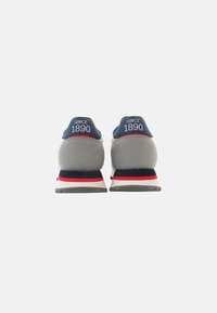 Námořnické a šedé sneakers s červenými akcenty; na zadní straně mají logo 'SINCE 1890'; zaoblený tvar, texturované materiály a odpruženou podrážku.
