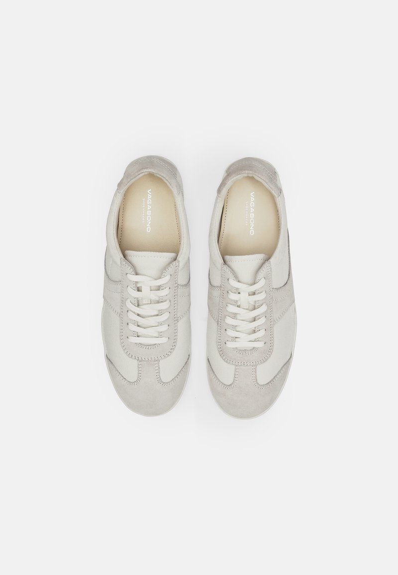 Jasnoszare trampki wykonane z zamszu i tkaniny, z białymi sznurowadłami, okrągłym noskiem oraz subtelnym detalem szwu na wierzchu.