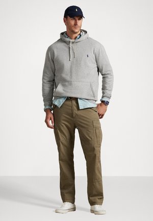 Hallhalli halliga sügisjakk, mille all on helesinine kraejope, oliivirohelised lahtised püksid ja valged tossud, kantud tumesinise mütsiga.