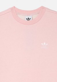 Gaiši rozā kokvilnas T-krekls ar apaļu izgriezumu un īsām piedurknēm. Krūšu daļā balta Adidas logo. Mīksta tekstūra ar minimālu dizainu.