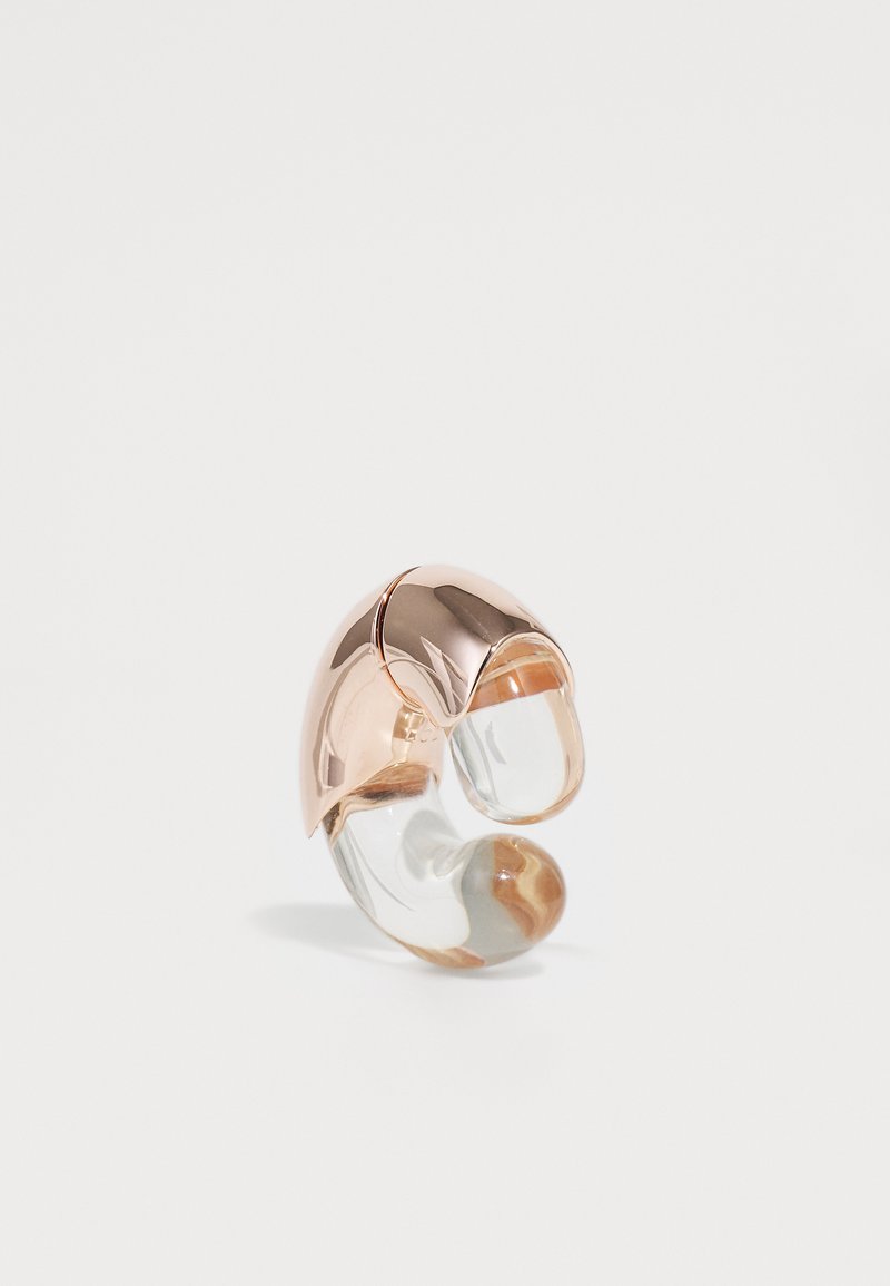 Gold-tone metal and clear resin abstract ring with curved shapes and smooth texture, featuring a marbled accent in brown and cream.