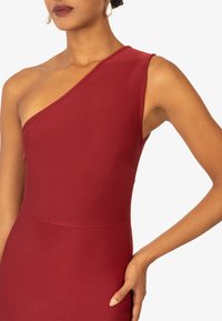 Czerwona sukienka na jedno ramię z gładkiego materiału, posiadająca dopasowaną górę, subtelną teksturę i czystą sylwetkę. Elegancki design z minimalnymi detalami.
