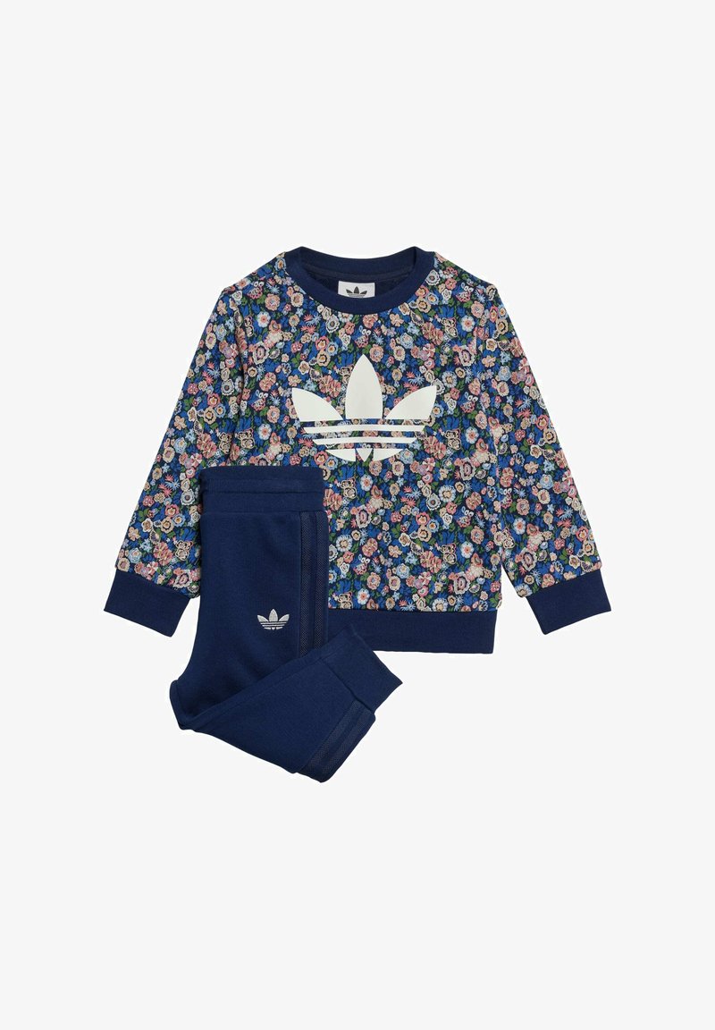 Sudadera de color azul marino con estampado floral y un logo blanco de Adidas, acompañada de pantalones a juego en azul marino. Tejido suave con puños y cintura acanalados.