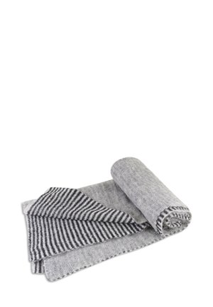 Pehmeä villahuivi vaaleanharmaana, mustilla ja valkoisilla vinoraidoilla, osittain auki valkoisella taustalla.