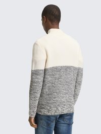 Knit sweater featuring a cream upper section and a textured gray lower half. Ribbed collar and cuffs, with a relaxed fit.