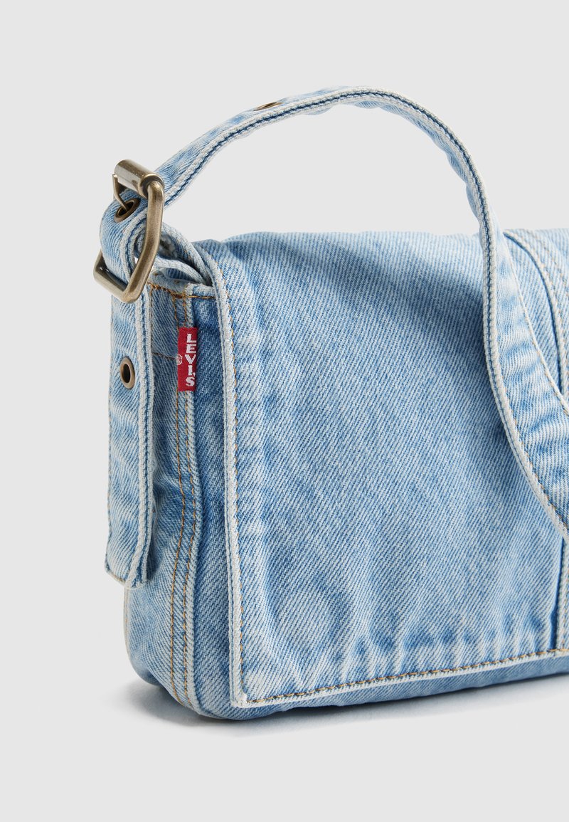 Borsa a tracolla in denim azzurro chiaro con tracolla regolabile, fibbia in ottone e etichetta con il logo rosso Levi's sul lato.