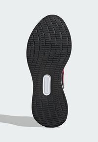 Black rubber shoe sole with a textured surface, featuring grooves for traction and a white accent near the heel.