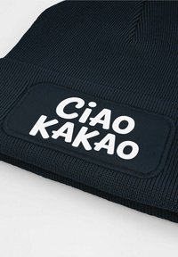 Knitted black beanie hat featuring a rectangular white patch with "Ciao Kakao" text in bold, rounded letters. Textured ribbed pattern.