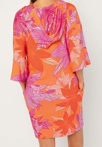 Vestido naranja de manga corta con capucha, que presenta un vibrante patrón floral en rosa y blanco, equipado con bolsillos laterales.