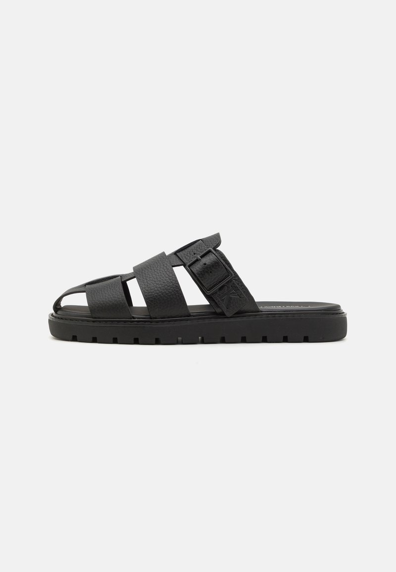 Black leather slide sandals with three straps, a buckled accent, and a textured footbed. Thick black rubber sole with a tread pattern.