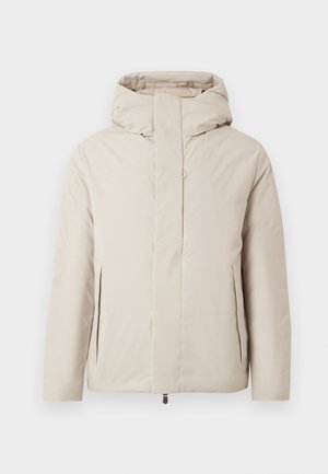 Bežs polsterēts jāketes ar augstu apkakli un kapuci. Tajā ir priekšējais rāvējslēdzis un sānu kabatas, izgatavota no gludas, ūdensizturīgas auduma.