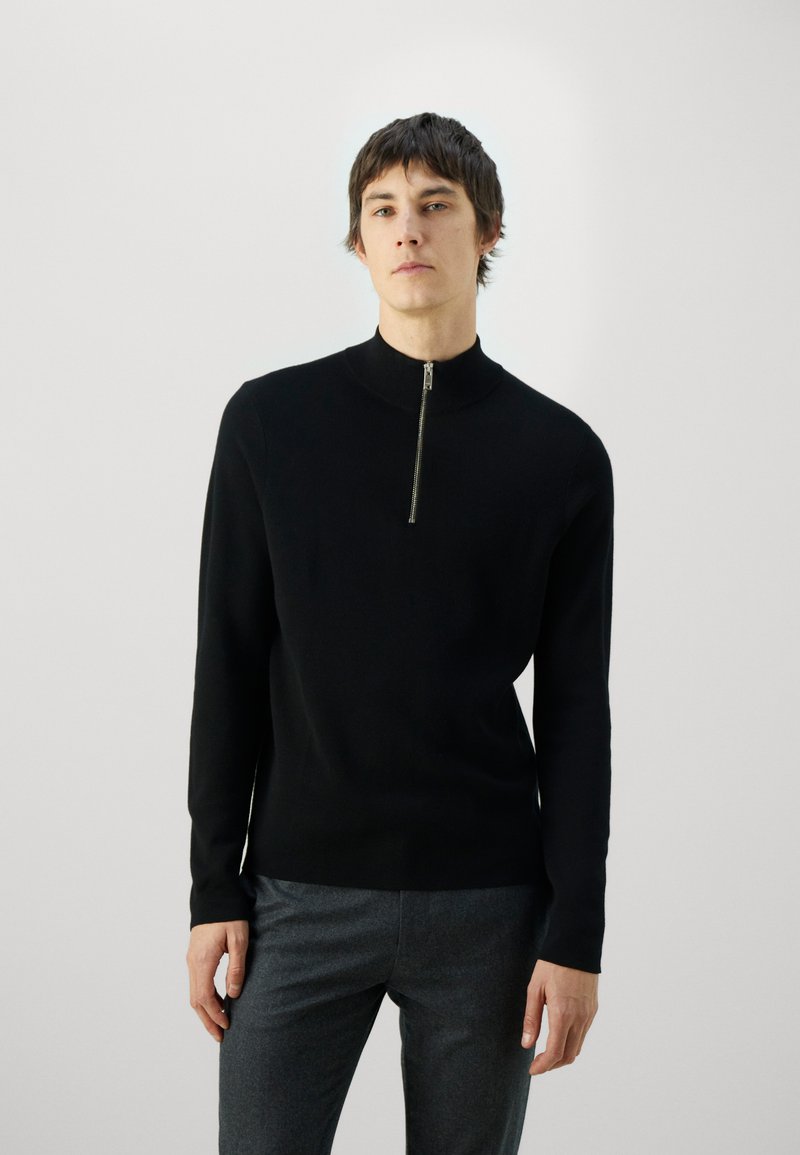 Black zip-neck sweater with long sleeves in a smooth knit material. Slim fit, features a high collar and minimalistic design.