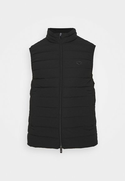 Vest puffer fără mâneci, de culoare neagră, cu un design matlasat vertical, guler înalt și fermoar frontal. Dispune de două buzunare laterale și branding minim.