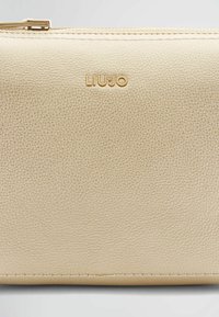 Portafoglio in pelle con texture dorata e zip di chiusura. Presenta il logo "LIUJO" impresso e un sottile dettaglio di cucitura lungo i bordi.