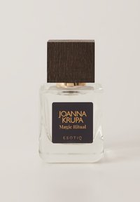 Kwadratowa szklana butelka perfum z czarną drewnianą nakrętką. Etykieta zawiera złoty tekst na ciemnym tle, przedstawiający "Magic Ritual" i "Esotiq."