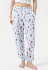Pantalons de pyjama bleu clair avec un motif rayé, ornés d'un motif coloré de macarons. Taille élastique avec cordon de serrage et poches latérales.