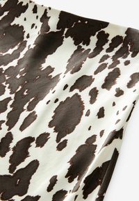 Tissu textur�é avec un motif de tache de vache en marron et crème, ayant un drapé lisse et fluide avec des tailles de taches variables.