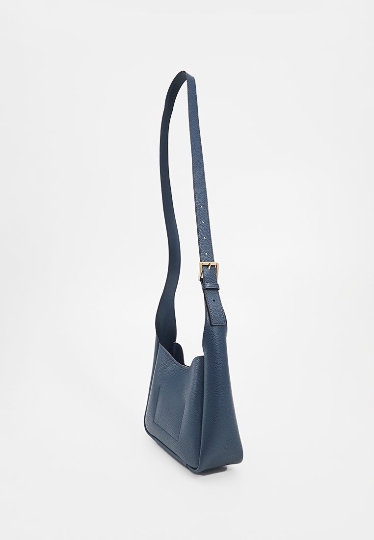 Sac à épaule en cuir bleu marine avec une finition texturée, une bandoulière réglable et une poche frontale plate. Design compact, forme élégante.