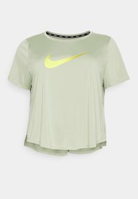 Vihreä Nike-t-paita, jossa on lyhyet hihat, pyöreä pääntie ja rohkea keltainen logo. Ominaisuuksiin kuuluvat musta brändätty kaulus ja sivuhalkiot.