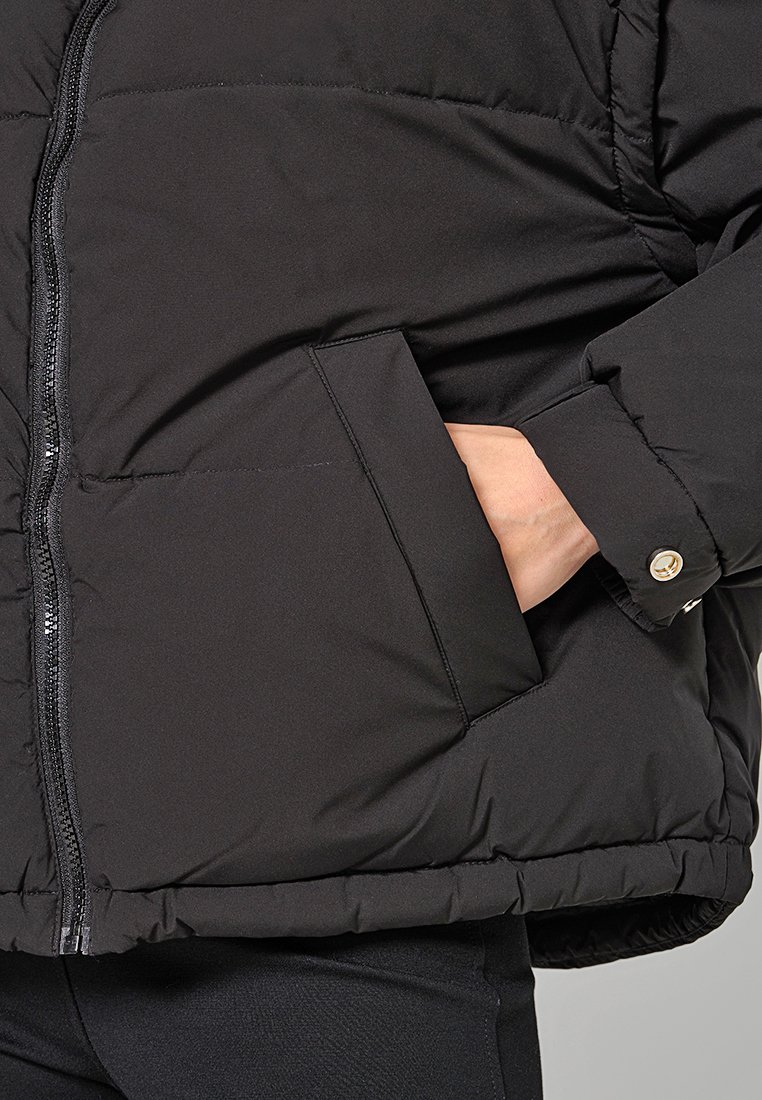 Schwarze Daunenjacke mit einem Reißverschluss, Stehkragen, Seitentasche und elastischen Bündchen. Glattes Material mit matter Oberfläche.