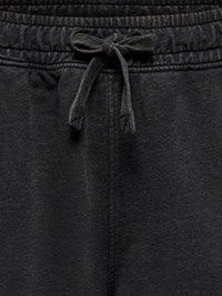 Gros plan sur la taille d'un pantalon de survêtement gris foncé avec une bande élastique et un cordon de serrage noué.