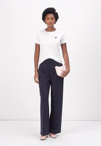 White short-sleeve t-shirt with maroon "LOVE" text, paired with navy wide-leg trousers. Model holds a light pink clutch. Smooth textures.
