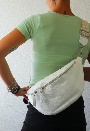 Witte leren crossbody tas met een gestructureerde afwerking, voorzien van een diagonale rits en een patroon op de verstelbare schouderband. Draagt op de rug.