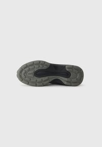 Black athletic shoe with a textured rubber sole. Sole features unique pattern for traction, and lower section is a dark grey color.