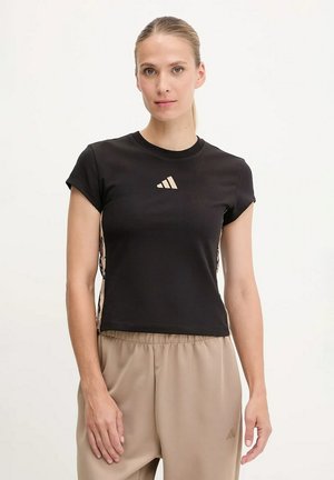 T-shirt nera a maniche corte con colletto rotondo, caratterizzata da un logo dorato sul petto e lati decorati. Abbinata a pantaloni beige.