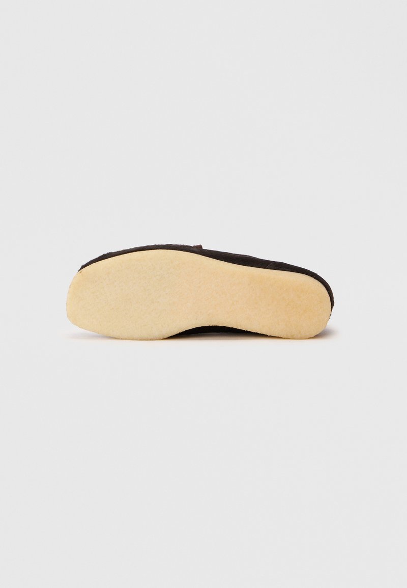 Black fabric slipper with a soft yellow sole, featuring a simple design and no visible hardware or patterns. The texture appears smooth.