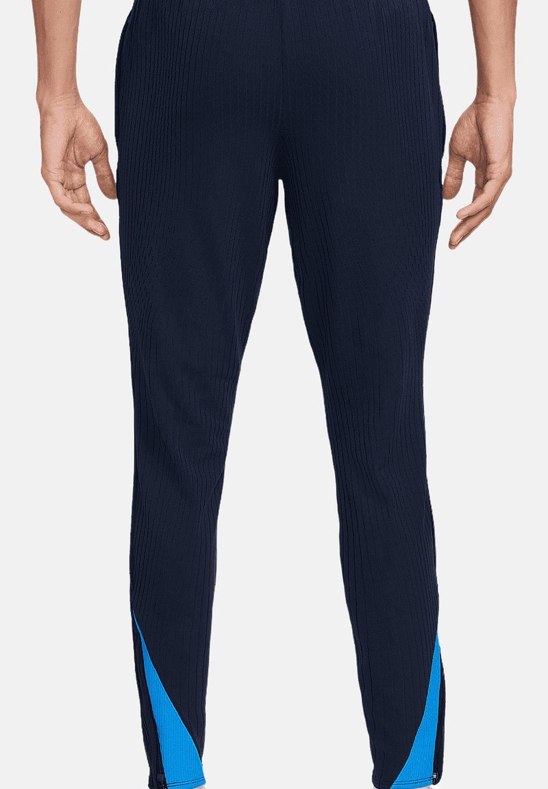 Pantalones deportivos de la marina con acanalado vertical, diseño ajustado y acentos laterales en azul. Cuentan con una cintura elástica y una silueta entallada.