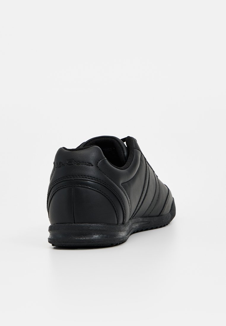 Zwarte leren sneaker met een textuur oppervlak, gebogen ontwerp en gevoerde kraag. Voorzien van een zwarte rubberen zool en subtiele naaddetails.