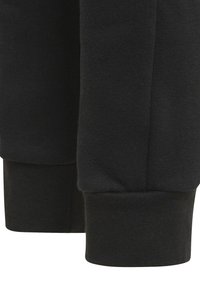 Närbild av svarta tygmanschetter med ribbad stickad textur på ärmarna av ett plagg, som visar sömdetaljer och sömlinjer.