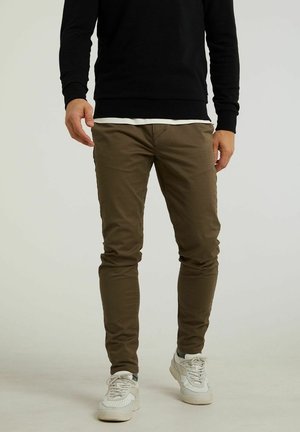 Khaki slim-fit pants made from cotton with front pockets and a smooth texture, paired with white athletic sneakers.