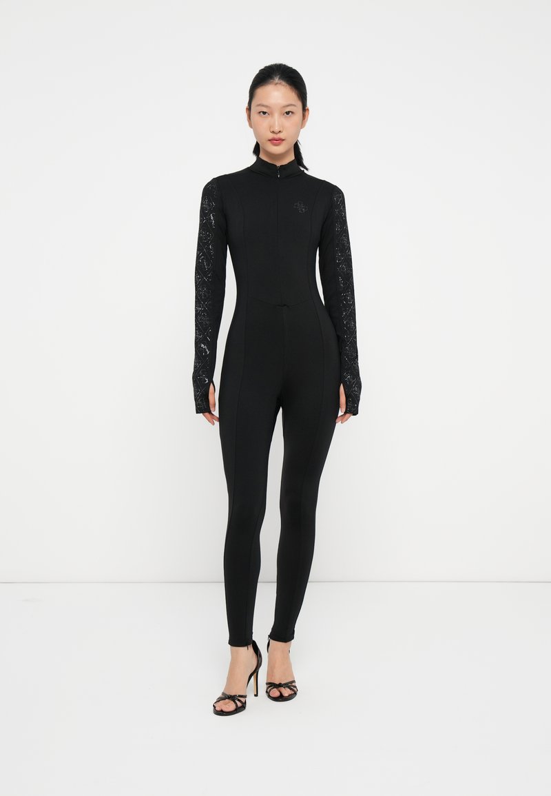 Svart helkropps jumpsuit med lange blonder ermer, høy krage, glidelås lukking og tettsittende design, med en subtil preget logo på brystet.