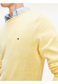 Lys gul sweater lavet af blødt stof med rund halsudskæring. Har et lille, broderet logo på brystet og ribbede manchetter.