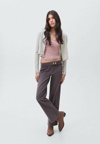 Svetlo siva skrajšana jakna, mauve top in temno sivi široki hlače z gumbi. Rjavih gležnjarjev je zaključek outfita.