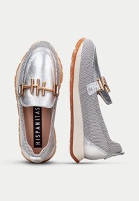 Hopeiset metalliset loaferit, joissa on verkkotekstuuri, kultainen solki ja ruskea kumipohja. Pyöreä muoto; minimalistische suunnittelu.