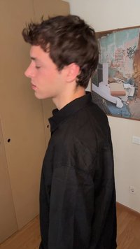 Črna, ohlapna srajca z visokim ovratnikom in dolgimi rokavi, ki ima gladko teksturo in minimalističen dizajn.