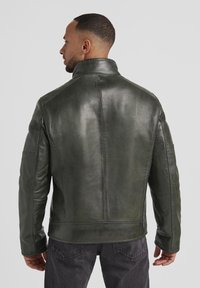 Grüne Lederjacke mit hohem Kragen, strukturiertem Design und Schulterakzenten. Hat eine strukturierte Oberfläche und Seitentaschen.