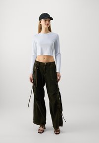 Lys blå langermet cropped topp paret med mørkegrønne cargo bukser med sidelommer og justerbare snorer. Svart caps og strappy hæler.