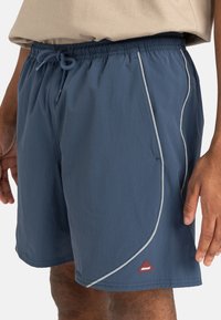 Herren Schwimmshorts aus dunkelblauem Nylon, mit einem elastischen Bund, Kordelzug und kontrastierenden hellgrauen Paspeln. Rotes Logo-Detail am Saum.