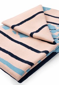 Złożony bawełniany koc, z miękkim brzoskwiniowym tłem i granatowymi oraz jasnoniebieskimi paskami. Teksturowana powierzchnia z detalami geometrycznymi.