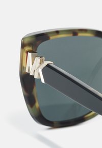 Ochelari de soare mari, pătrați, cu un cadru din plastic cu imprimeu țestoasă, accente din metal aurit și lentile întunecate. Dispune de brațe elegante de culoare neagră.